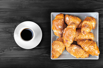 Breakfast flatlay, croissants and coffee on black wooden table