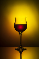 A glass on the high leg for red wine on a gradient yellow-red background.
