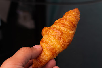 Man holding croissant against black background - breakfast moment