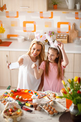 Mother whith daughter making selfi while painting eggs