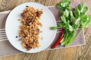 mutton pilav served with hot pepper and fresh cilantro on wooden background
