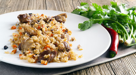 mutton pilaf served with hot pepper and fresh cilantro on wooden background