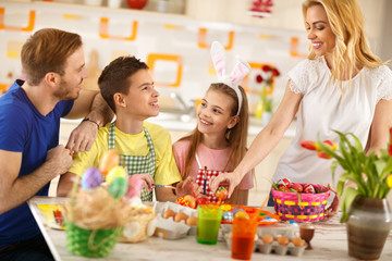 Woman with family preparing Easter basket with eggs
