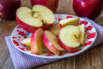 Fresh organic big red apples whole and sliced on wooden table