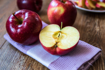 Fresh organic big red apples whole and sliced on wooden table