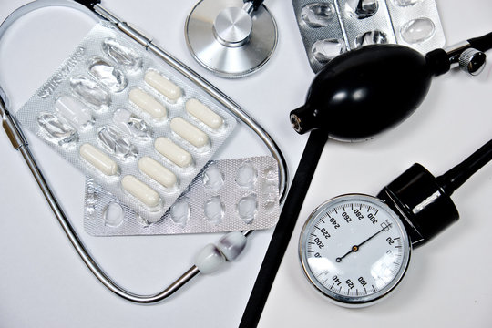 phonendoscope and tonometer  with a folder with white sheets of paper and pills  on a white background