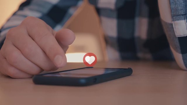Close up of young man using smartphone with likes and loves icon floating out of smart phone