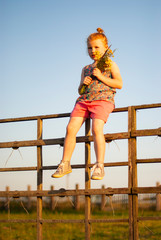 Fototapeta premium a child, a girl climbs a wooden fence in the village.