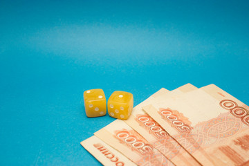Amber dices with ruble banknotes on blue background