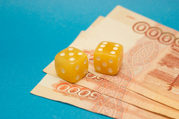 Amber dices with ruble banknotes on blue background