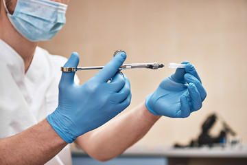 Bettering the Human Condition. Hands of dentist holding dental syringe