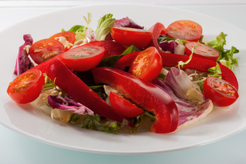 Salad with fresh vegetables on a white table