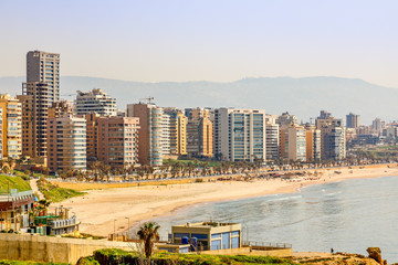 Obraz premium Budynki i wieże śródmieścia z drogą, piaszczystą plażą i morzem na pierwszym planie, Bejrut, Liban