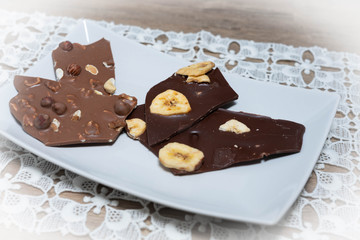 Vollmilch- und Zarbiterschokolade mit Nüssen und Banane auf einem weißen Teller