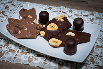 Vollmilch- und Zarbiterschokolade mit Nüssen und Banane auf einem weißen Teller
