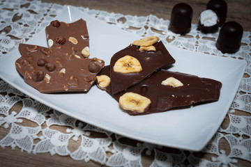 Vollmilch- und Zarbiterschokolade mit Nüssen und Banane auf einem weißen Teller