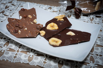 Vollmilch- und Zarbiterschokolade mit Nüssen und Banane auf einem weißen Teller