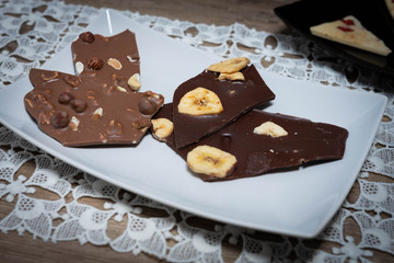 Vollmilch- und Zarbiterschokolade mit Nüssen und Banane auf einem weißen Teller