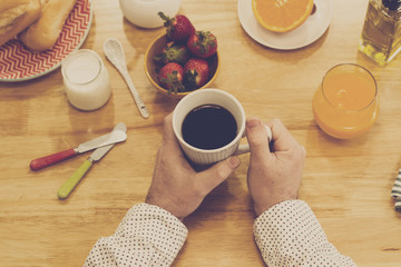 Manos de hombre con café vista de arriba sobre mesa de madera