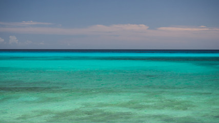 The gentle turquoise ocean water to the horizon and the blue sky is a tropical Dominican landscape.
