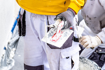 Construction worker plastering and smoothing concrete wall with cement