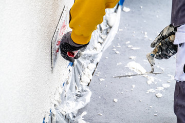 Construction worker plastering and smoothing concrete wall with cement