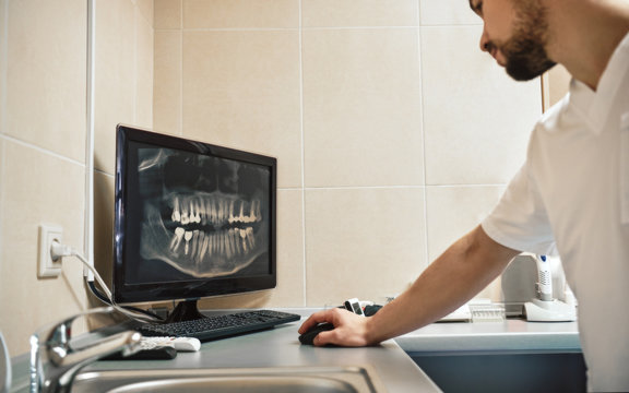 Dentistry with heart. Dentist looking at the X-ray picture of jaws on digital computer monitor