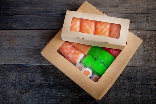delivery service Japanese food rolls in cardboard box on a wooden background