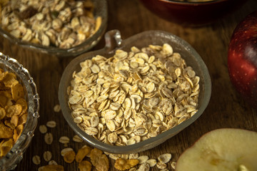 Close up photo of a cereal grain product. Barley flake from whole grain for barley porridge, fresh organic red apple, muesli and corn flakes.
