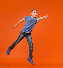 Fototapeta na wymiar Energetic boy jumping and pointing hand to empty space aside