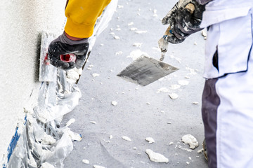Construction worker plastering and smoothing concrete wall with cement