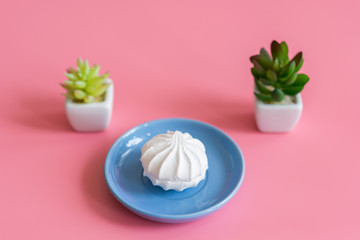 White cake in a blue plate on a pink background