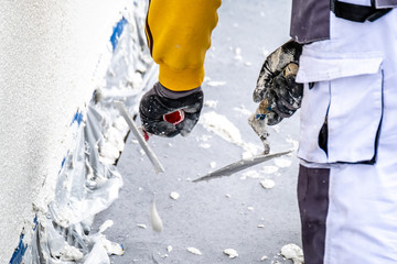 Construction worker plastering and smoothing concrete wall with cement