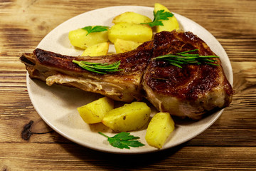 Roasted beef rib eye steak on bone with baked potatoes and herbs on wooden table