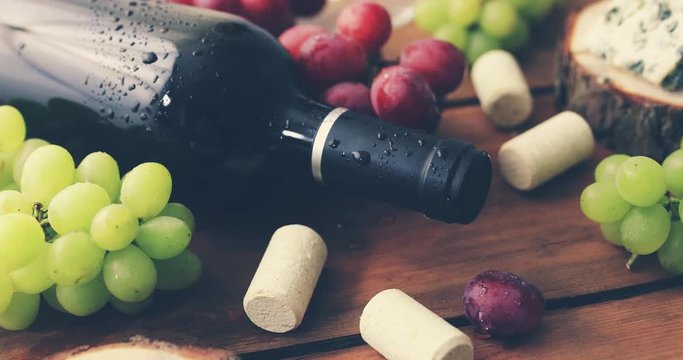 red wine bottle with grapes on old wooden background