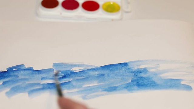 Woman artist painting with watercolor paints. The artist the painting close up of a brush on paper. Art Studio brushes and watercolor paintings.