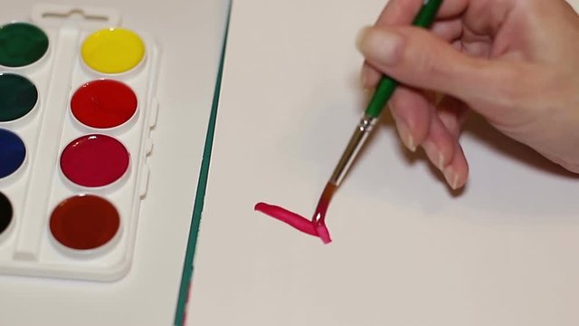 Woman artist painting watercolor paints the word love.  The artist the painting close up of a brush on paper. Art Studio brushes and watercolor paintings.