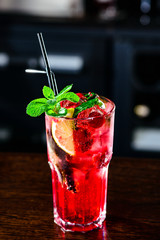 Raspberry pink Mojito Lemonade with lime and fresh mint in glass on bar counter in a nightclub. Summer refreshing cocktail.