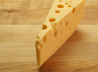 Cheese with big holes on a wooden table