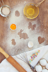 Traces of flour or powdered sugar in the form of Easter figures on the kitchen table in the process of preparing a feast for the feast with products and kitchen appliances and tools. Top view, flatlay
