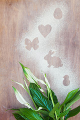 Traces of flour or powdered sugar in the form of Easter figures on the kitchen table in the process of preparing a holiday for the holiday with a beautiful spatifilum. Top view, flat lay