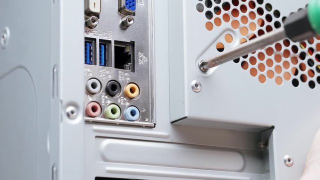 Close-up computer assembly. A male service worker installs a fan in a PC case. Tighten the screw with a screwdriver.