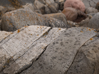 Granite rock with diagonal cracks and out of focus boulders in background