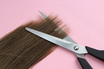 A strand of hair lies with scissors to cut the ends