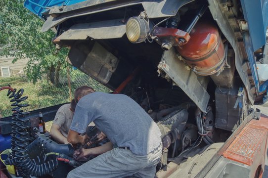 breakdown in the countryside away from the city, two men repair the truck, work hard on a hot day