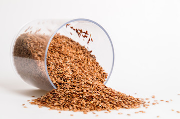 Close up. Capacity for spices lies near a pile of flax seeds. White background. Copy space.