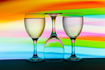 Three wine glasses in a row with colorful light painting behind