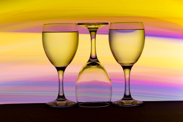 Three wine glasses in a row with colorful light painting behind