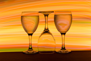 Three wine glasses in a row with colorful light painting behind