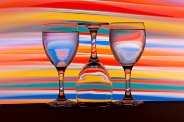 Three wine glasses in a row with colorful light painting behind